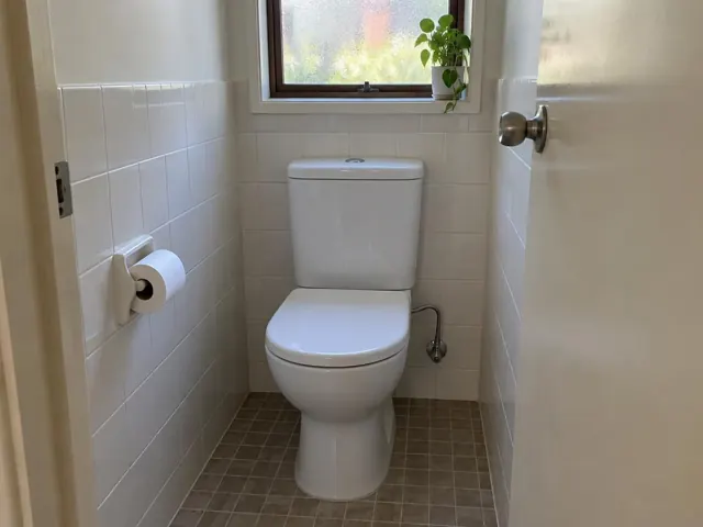 Clean white toilet in a small tiled bathroom with a window and toilet roll holder in Kings Langley