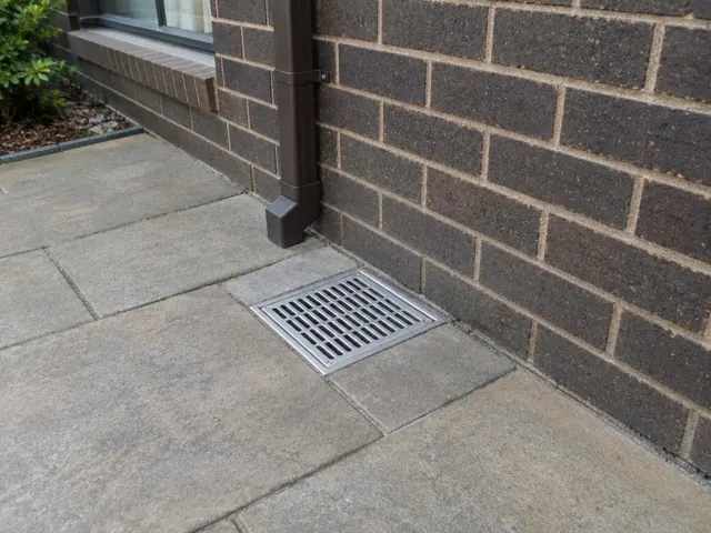 Outdoor grated gully beside brick wall on dry paving in Lalor Park